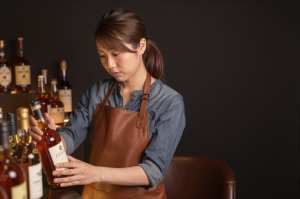 ウィスキーバーでボトルを選ぶ女性