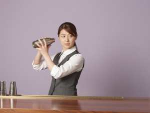 バーカウンターでカクテルを作る女性