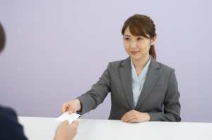 ホテルの受付で鍵を渡す女性