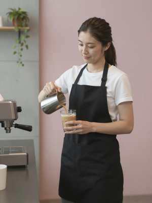 モダンカフェでアイスラテを作る女性