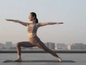 屋上ヨガで日の出を浴びる女性