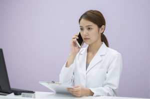 薬局で電話応対する薬剤師