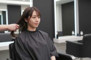 ヘアサロンで髪を梳かれる女性