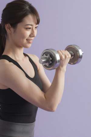 集中してダンベルカールをする男性