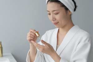 手のひらに美容オイルを垂らす女性