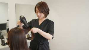 前ボケ越しにヘアブローする美容師