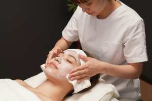 フェイシャルマスクを拭き取るエステティシャン