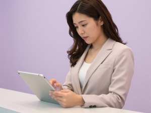 ホテルでタブレットを使って接客する女性