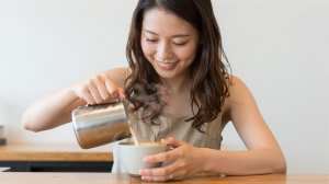 ラテアートを注ぐバリスタの顔のクローズアップ