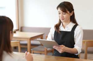 カフェでタブレットで注文を取る女性