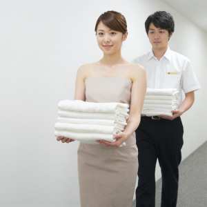 ホテル廊下でタオルを運ぶ男性スタッフ