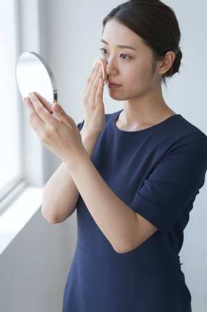 自然光の下でファンデーションを塗る女性