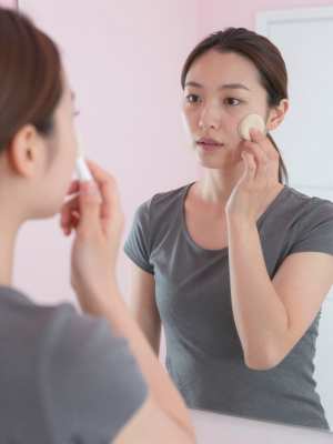 鏡越しに洗顔ブラシで角質ケアをする女性