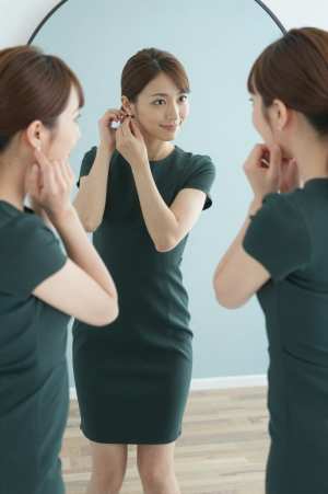鏡でイヤリングを調整する女性