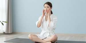 ヨガマットでフェイシャルマッサージをする女性