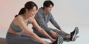 ジムのマットで脚をストレッチする男性