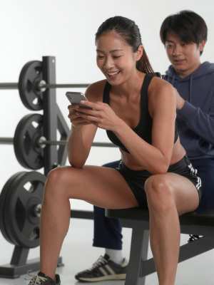 ジムのベンチでスマホを見る男性の顔