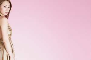 ピンク背景の金髪女性が振り返るポートレート