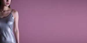 ピンク背景のシルクドレス姿の女性ポートレート