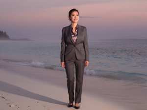 夕暮れ時のビーチで微笑むビジネススーツの女性ポートレート