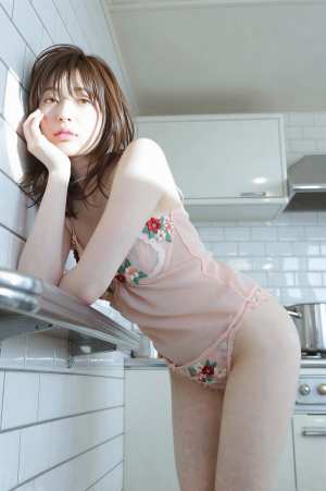 キッチンでポーズをとる若き女性のグラビア写真