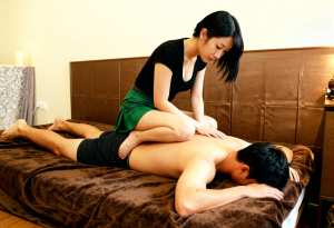 寝室のベッドに横たわっている男性に女性が親密なマッサージを施す様子を、トップダウンの...。