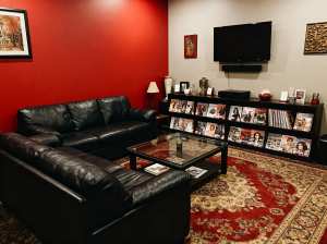 赤い壁と黒い革製の家具 (黒い革製のセクショナル ソファやガラスのコーヒー テーブル...。