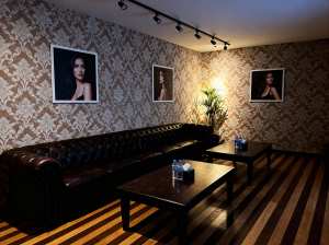 薄暗い部屋に、茶色の革張りのソファ、水の入ったボトルが置かれた 2 つの木製テーブル...。