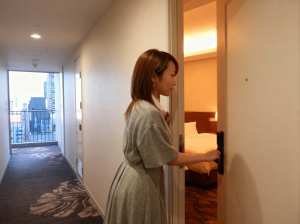 ライトグレーのドレスを着た長い茶色の髪の若い女性が、街のスカイラインを望むバルコニー...。
