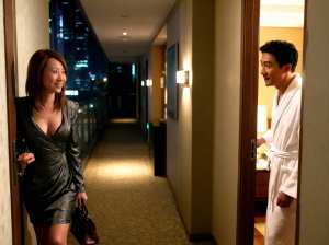 夜のホテルの廊下で笑顔で見つめ合うカップルをサイドカメラアングルから写実的に撮影。