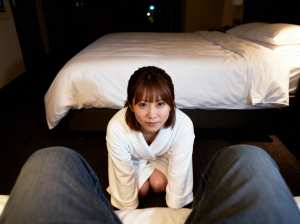 ホテルの一室で床にしゃがみ、無表情でカメラをまっすぐ見つめている若い女性をローアング...。