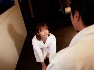 ホテルの一室で床にひざまずき、目の前に立つ男性をじっと見つめる白いローブを着た若い女...。