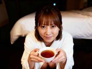 顔の前でお茶を持っている若い女性に焦点を当てた、ローアングルからのクローズアップショット。