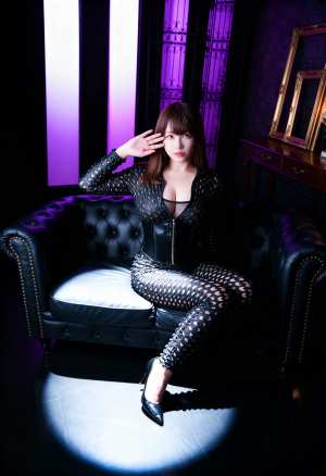 紫色の照明が照らされた薄暗い部屋で、黒い革張りのソファに座っている女性を正面カメラの...。