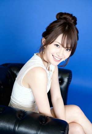 明るい青色の背景に黒い革張りのソファに座っている若い女性をポートレート角度から撮影し...。