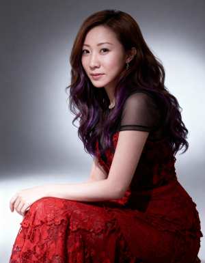 赤いレースのドレスを着て、グラデーションの背景に対して瞑想的なポーズで座っている、ウ...。