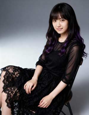 薄手の黒いトップスと長い黒いレースのスカートを着て、リラックスしたポーズで椅子に座っ...。