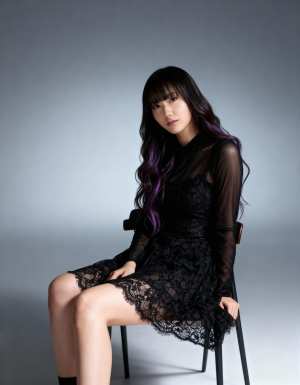 ミニマルな環境で黒いレースのドレスを着て椅子に座っている若い女性を正面カメラのアング...。