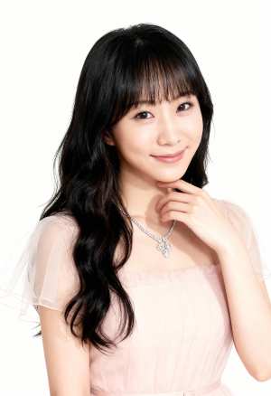 ウェーブのかかった長い黒髪と前髪を持ち、薄手の袖と繊細なネックレスが付いた淡いピンク...。