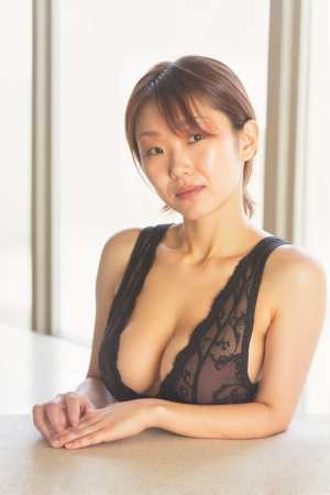 テーブルに座り、わずかな笑みを浮かべてカメラを直接見つめている若い女性をポートレート...。