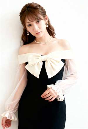 薄手の袖と大きなリボンが付いたフォーマル ドレスを着て、真っ白な壁に向かってポーズを...。