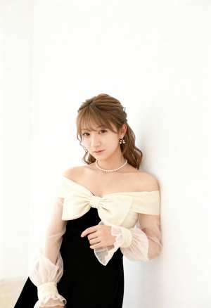 薄手の袖と大きなリボンが付いたフォーマルな衣装を着て、無地の白い壁に向かってポーズを...。