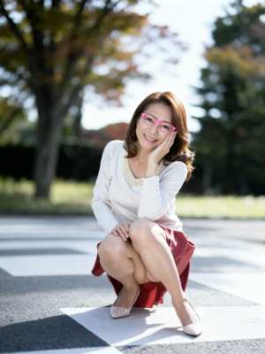 ピンクの眼鏡と真珠のネックレスが付いた白いセーターを着て、公園の横断歩道でしゃがむ若...。