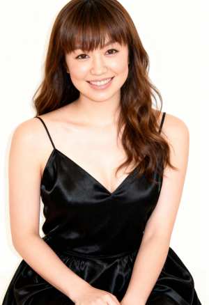 ウェーブのかかった長い茶色の髪と前髪を持つ若い女性のポートレート。