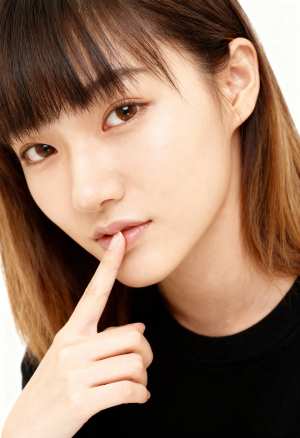 指を唇に押し当ててポーズをとる、思慮深い表情をした若い女性の接写。