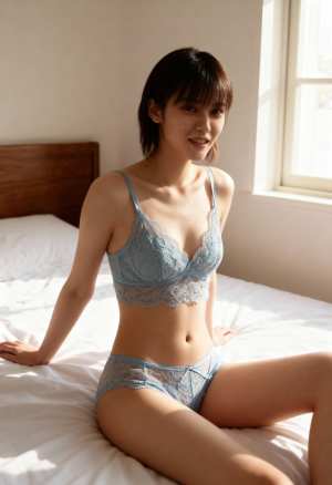 水色のレースのランジェリーセットを着てベッドに座り、ほんのり微笑みながらカメラを見つ...。