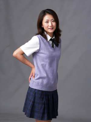 無地のグレーの背景に自信を持ってポーズをとる学生服を着た若い女性を、全身カメラ アン...。