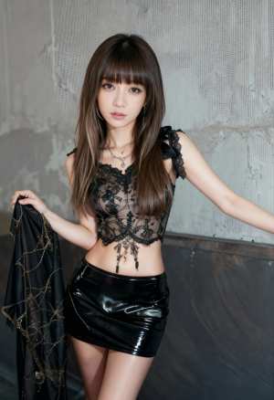 薄手の黒いレースのトップと光沢のある黒いミニスカートを着て、質感のあるコンクリートの...。