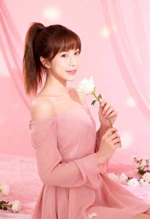 柔らかなピンクの背景に、ドレープ生地と白い花が描かれた白いバラを持った若い女性を、正...。