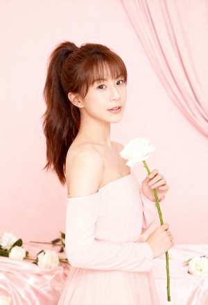 柔らかいピンクの背景に白い花を持つ若い女性をポートレート カメラの角度から撮影した写...。